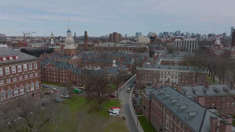 Forwards fly above buildings with red brick style facades. Aerial view of Harvard University campus complex. Boston, USA