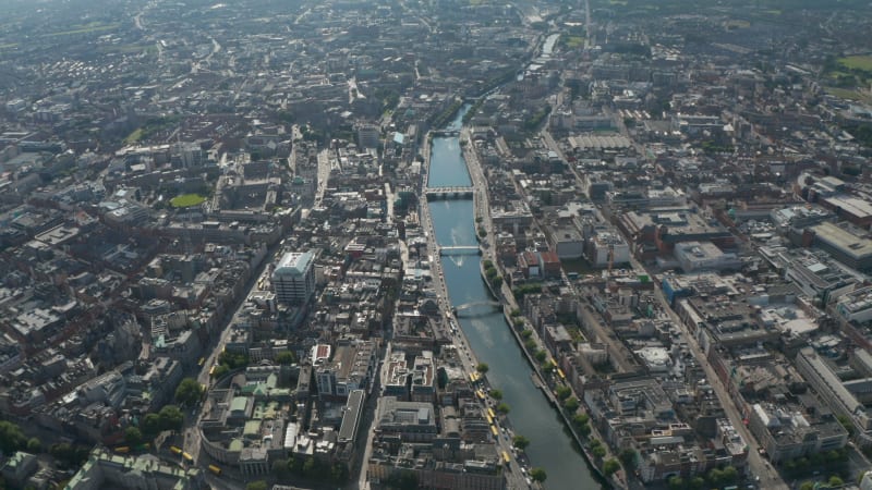 Aerial panoramic footage of Liffey river calmly flowing through city. Large town from height. Dublin, Ireland