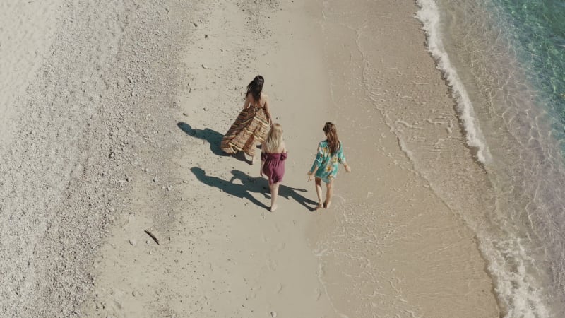 Aerial view of three women along the shoreline in Calabria, Italy.