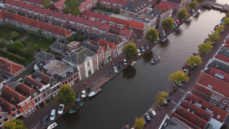 A boat moving on a canal in a residential area of Leiden, South Holland, Netherlands.