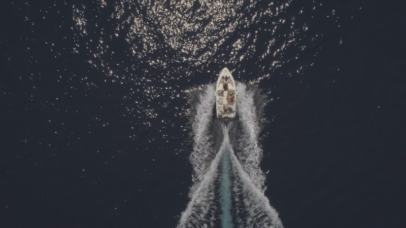 Aerial view of small speed boat with trailing wake on sea.