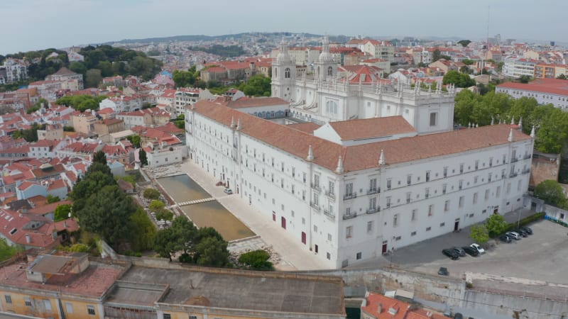 Aerial establishing orbit of white monastery of Sao Vicente de Fora church building on the hill in city center of Lisbon, Portugal