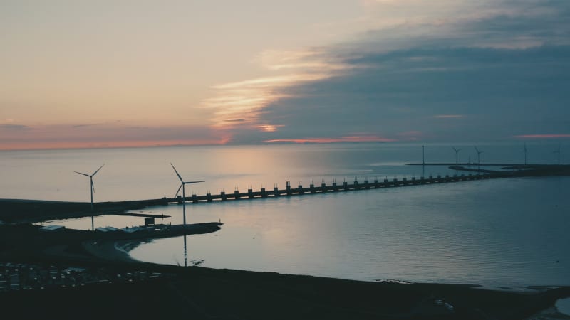 Aerial view of the Delta Works with windmills on the side on a calm morning