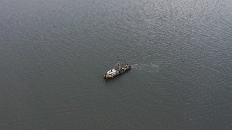 Idle fishing boat isolated against the rippling ocean surface