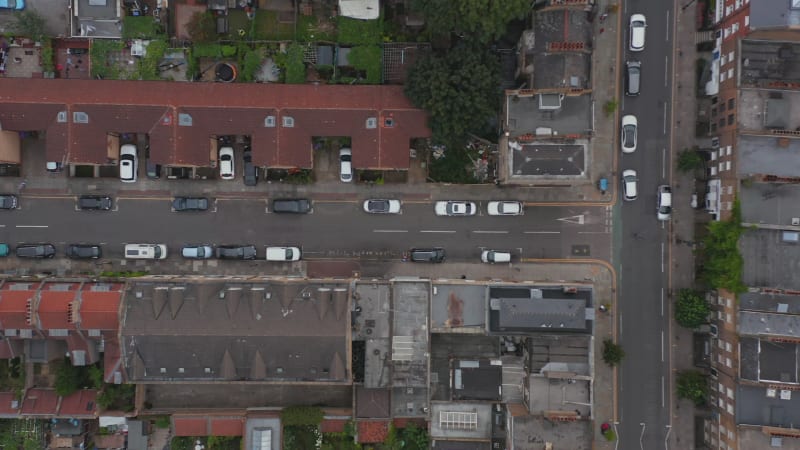 Aerial birds eye overhead top down panning view of car driving in narrow town streets and crossroads. London, UK