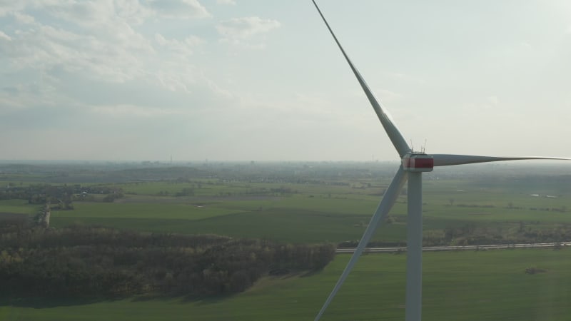 close up shot of wind mill rotating by the force of the wind and generating renewable energy in a green ecologic way for the planet over beautiful green Agriculture field