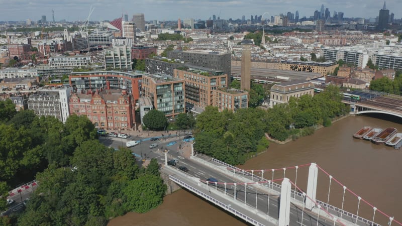 Aerial view of traffic on road intersection near Chelsea bridge. Mixture of old and modern residential buildings. Downtown skyscrapers in background. London, UK