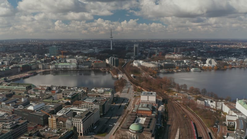 Wide aerial view of car and train traffic across Binnenalster lake with Hamburg panorama in the background