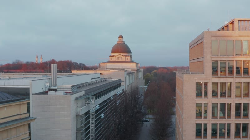 The Bavarian government or Staatskanzlei Building in Munich, germany in beautiful Sunset light with view above English Garden Public Park in Winter, Aerial Crane rising up revealing Cityscape