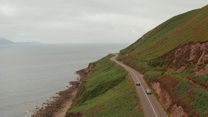 Amazing panoramic route above cliffs along Slea Head coast. Forwards tracking of car on road traversing slope. Ireland