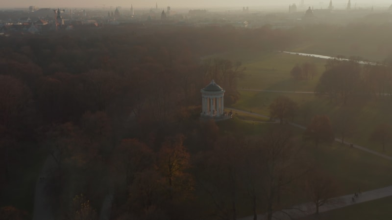 Scenic Aerial View over Munich Cityscape from English Garden Public Park in beautiful Winter Haze, Aerial slow tilt up establishing Shot