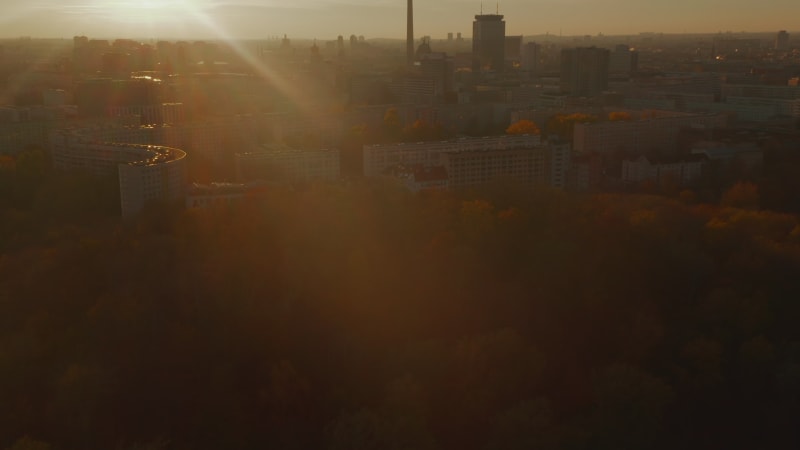 Autumn Fall Colored Sunset and Nature in Big City with TV Tower Skyscrape in center of Berlin, Germany. Aerial Dolly out above beautiful Cityscape in Golden light