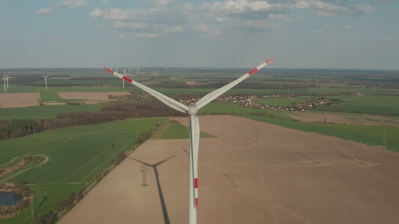 Close up shot of wind Turbine, Mill rotating by the force of the Wind Generating Renewable Energy in a Green Ecologic way for the Planet over beautiful Green Agriculture field