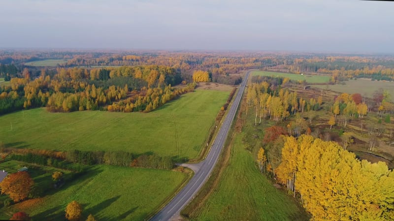 Aerial view of road crossing between agricultural land and village.