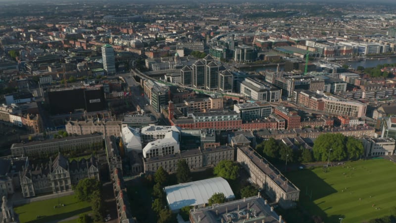 Backwards fly above Trinity College area. Historic buildings, squares and green parks. Aerial panoramic view of city. Dublin, Ireland