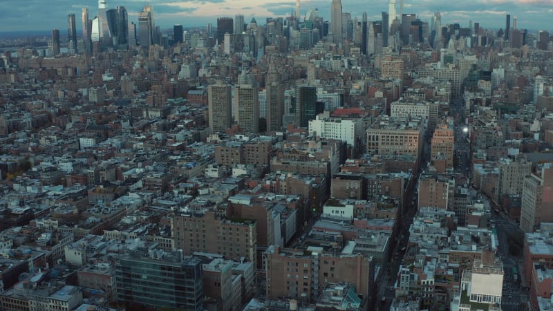 Forwards fly above city development. Tilt up reveal of morning skyline with downtown skyscrapers at dawn. Manhattan, New York City, USA