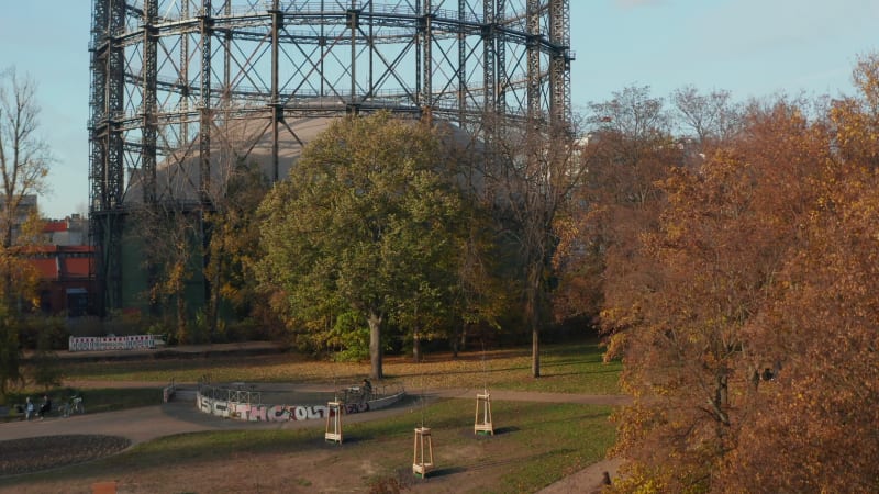 Famous Gasometer in Berlin, Germany surrounded by Autumn colored Trees and Nature in Big City, Aerial lift up revealing shot