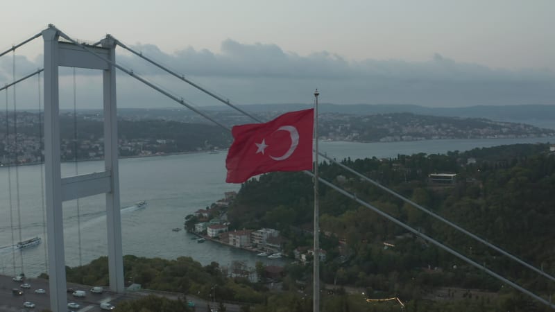 Turkish Flag Waving in Wind in front of Istanbul Bosphorus Bridge, Aerial medium shot slide right