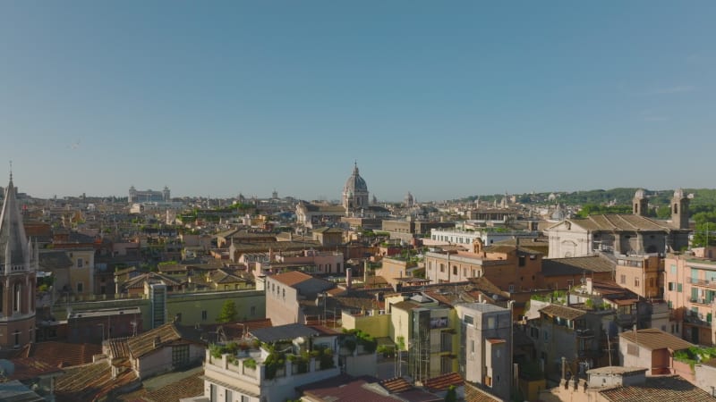 Fly above historic urban borough at golden hour. Colour residential buildings lit by morning sun. Rome, Italy