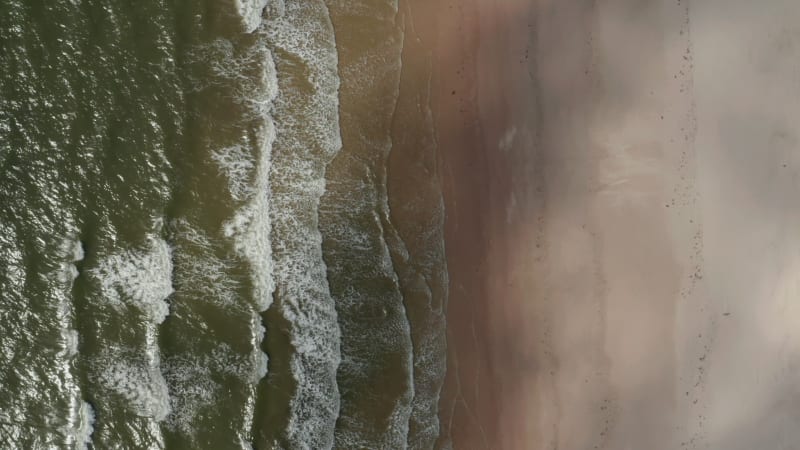 Aerial birds eye overhead top down view of waves rolling on coast. Sea water washing sandy beach. North sea shore. Denmark