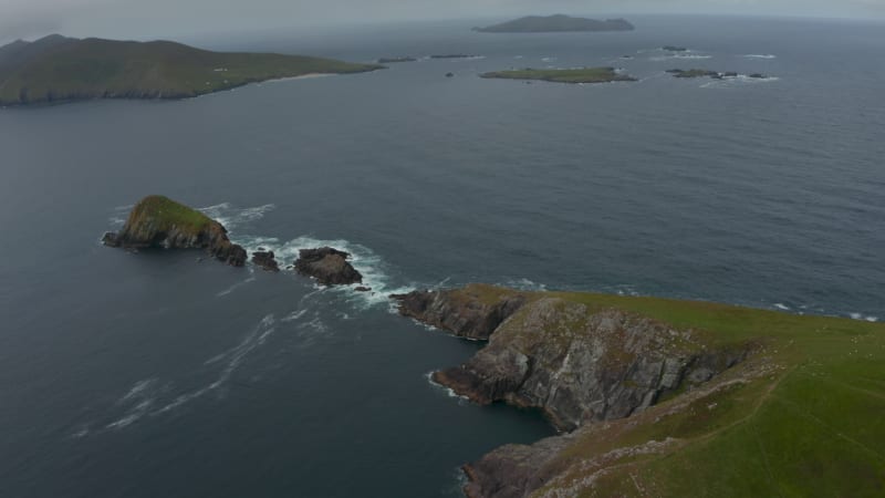 Aerial panoramic footage of islands in sea near coast. Green grass with rocky cliffs on Dunmore Head promontory. Ireland