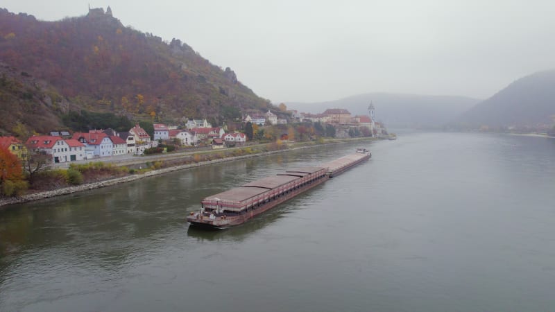 Cargo Pusher Boat on a River Transporting Cargo and Goods Past a Town