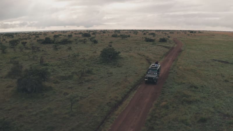 Woman riding on top of offroad vehicle in wild African landscape