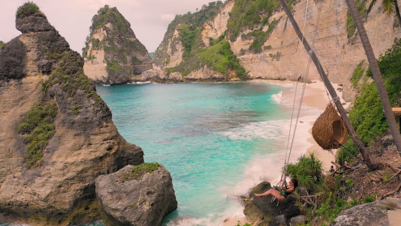 Aerial view of attractive woman swinging at Diamond Beach shore.