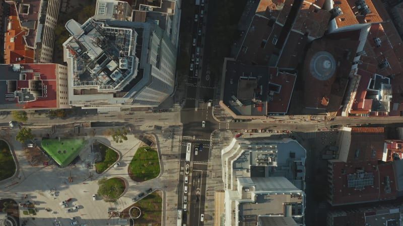 Aerial birds eye overhead top down ascending view of traffic at Torre de Madrid at Spain Square at golden hour. Cars and pedestrians in city centre.