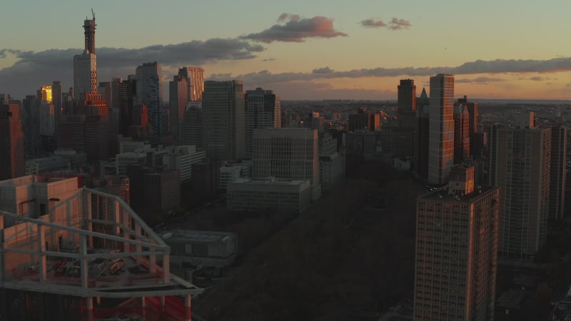 Fly above tall office or apartment buildings in city at dusk. Silhouettes of high rise towers against colourful twilight sky. Brooklyn, New York City, USA