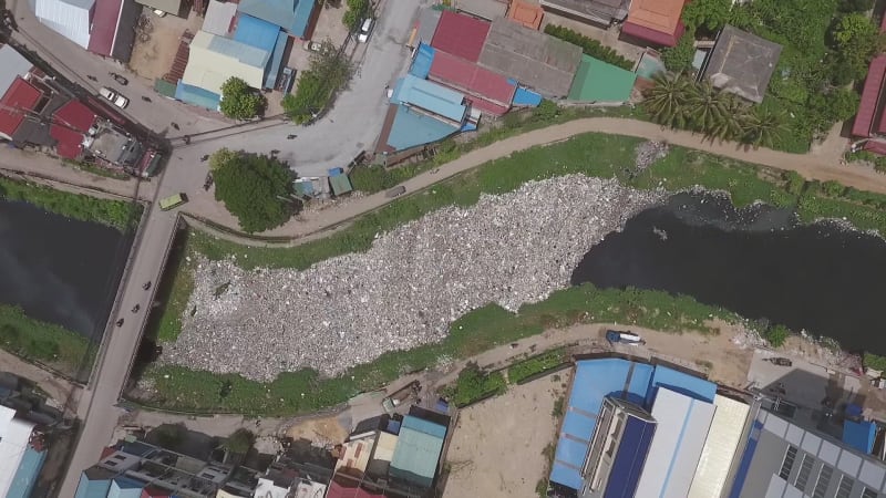 Aerial view above of polluted river crossing city.