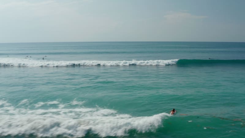 Fast ocean waves breaking on the sea. Surfers floating on the surf boards in tropical ocean