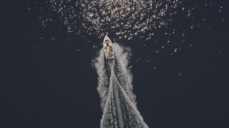 Aerial view of small speed boat with trailing wake on sea.