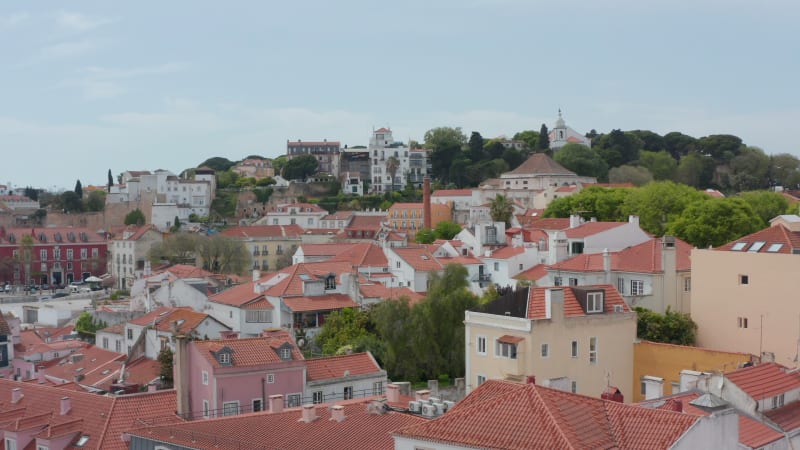 Slow aerial dolly in view of luxury traditional colorful houses on the hills surrounding dense urban city center of Lisbon, Portugal