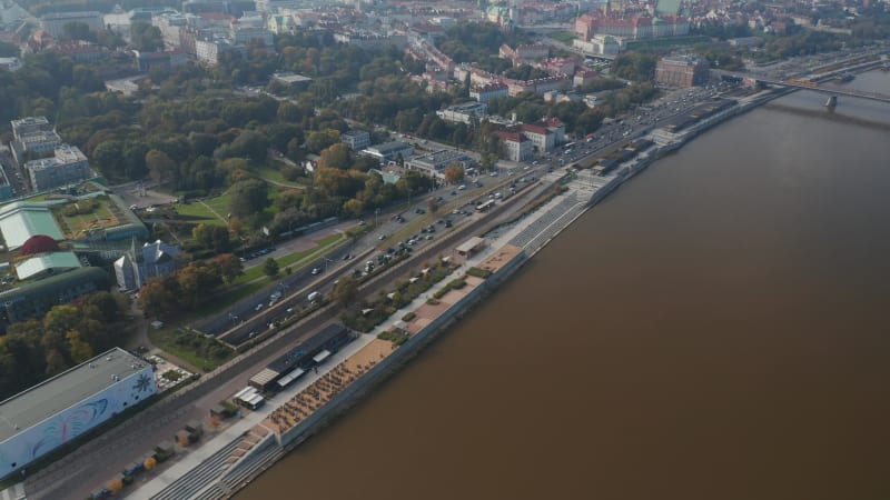 High angle view of heavy traffic on trunk road leading along Vistula river. Tilt up reveal cityscape with Royal Castle. Warsaw, Poland