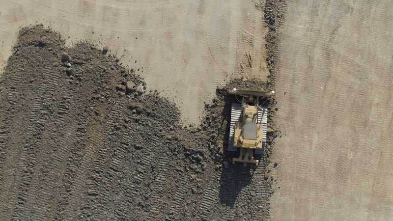 A Bulldozer Moving Earth to Flatten it for Construction