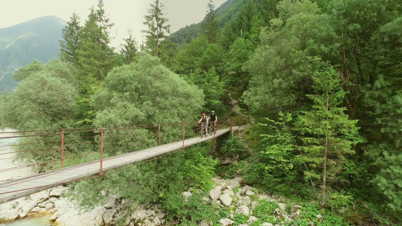 Aerial view of a couple crossing a wooden bridge on bicycles.