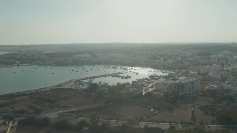 Bay with Boats and Sun reflecting on Water at Sunset on mediterranean Malta Island, Aerial Drone View