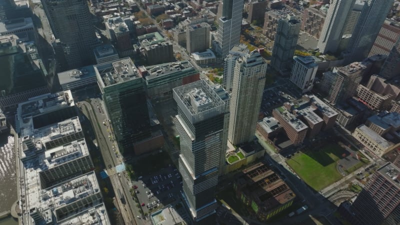 Aerial footage of high rise town development at waterfront. Water surface reflecting sun. Jersey City, USA