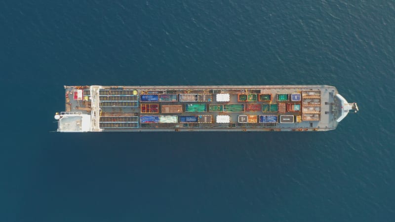 Cargo Ship loaded with colourful Containers and large crates cruising at sea