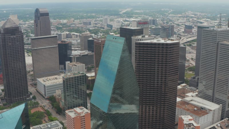 High angle view of sharp ridge on top of tall glass covered unusual shape building. Tilt down at Fountain place skyscrapers. Dallas, Texas, US