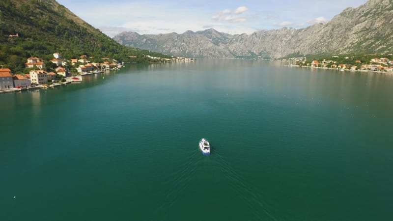 Small Fishing Boat in a Mountainous Bay Rising Aerial