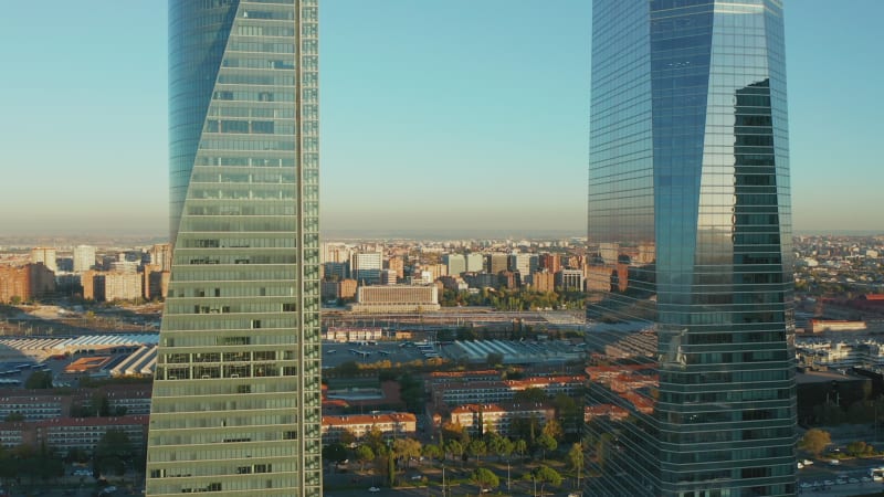 Forwards fly between two modern office towers. Revealing large logistic site and train station.  Town development at golden hour.