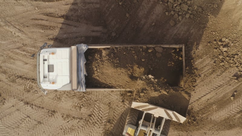 Excavator loading Trailer Truck with a load of Soil, Aerial view.