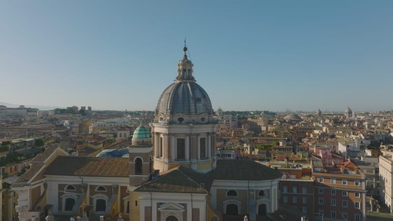 Circular flight around San Carlo al Corso basilica. Old buildings in historic city centre lit by morning sun. Rome, Italy