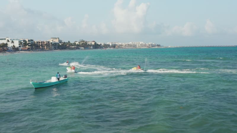 Couples finishing their jet ski ride and cruising back to the beach. Aerial view with watercrafts on the Caribbean Sea