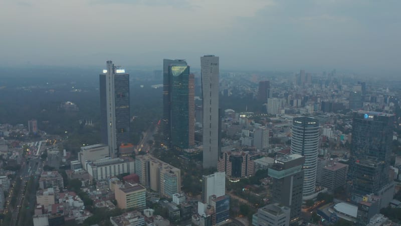 Forwards fly above city. Heading towards group of downtown skyscrapers. Aerial view of tall office buildings and large park behind. Mexico City, Mexico.