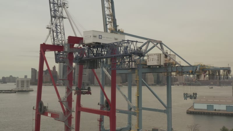 Close Up of industrial cranes in docks with New York City with skyline in background and river