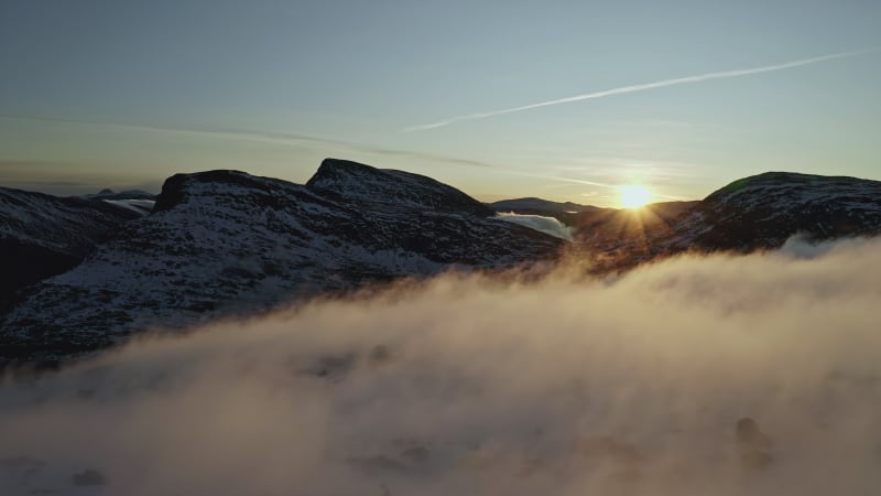 Fog over mountain during sunset in Norway.