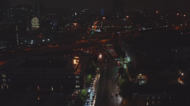 Aerial view of city night scene. Drone flying above street towards multi lane freeway, tilting down on driving cars. Traffic at night. Dallas, Texas, US